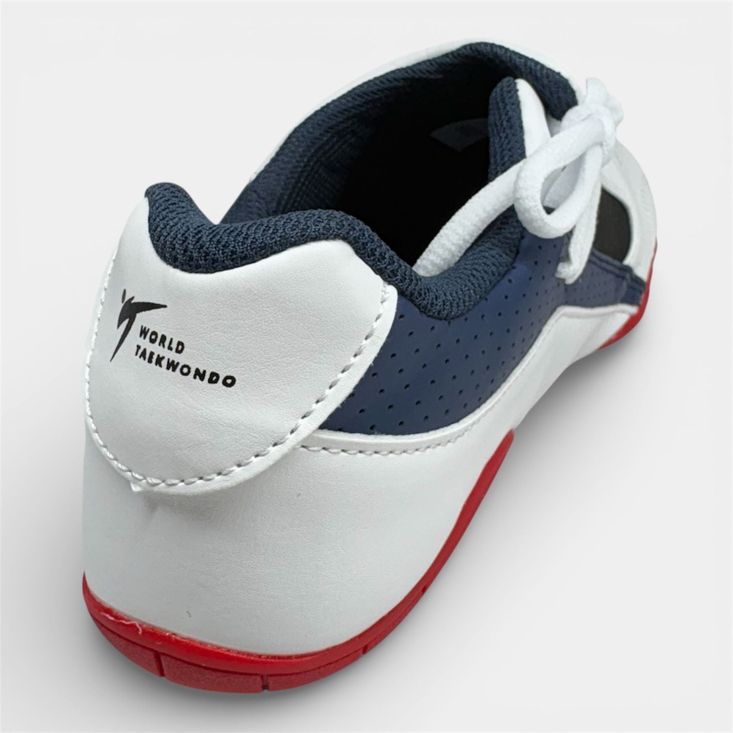 White taekwondo shoe with navy accents and red sole on a light gray background